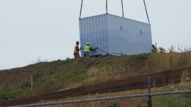 shipping container hanging being placed on mountain outside 