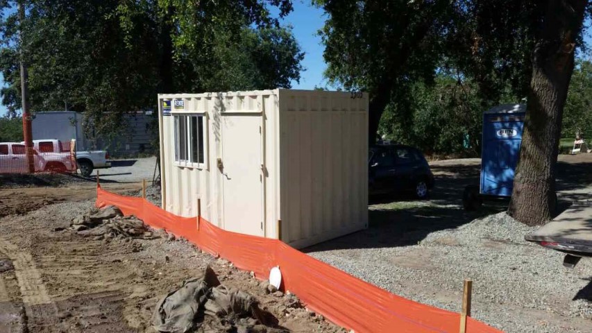 contracted use shipping container storage container office container window man door orange tape mud dirt trees