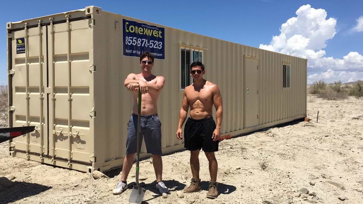 blue skies shipping container with shirtless men 